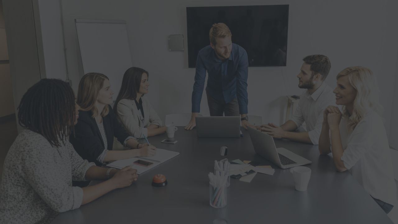 Reunião de trabalho em torno de uma mesa, com pessoas discutindo o andamento de um contrato